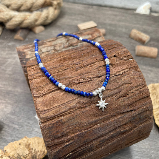 STAR SHINNERS COLLIER EN PERLES DE LAPIS-LAZULI FACETTÉES AVEC PENDENTIF ÉTOILE DU NORD PAVÉE D'UN ZIRCON CENTRAL ET ARGENT 925