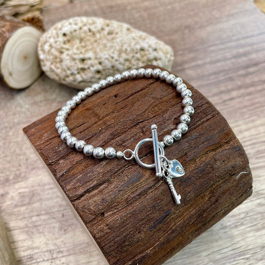 Bracelet femme LOCKED WITH CURBY – perles boules 6 mm & pendentifs clé & cadenas cœur, fermoir toggle et argent 925 – bijoux fait main en argent 925 | Pitch & Néo